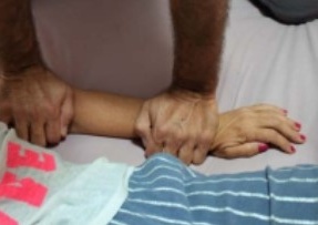 Les mains du praticien exercent une pression ferme sur l'avant-bras de la personne allongée, le long des méridiens